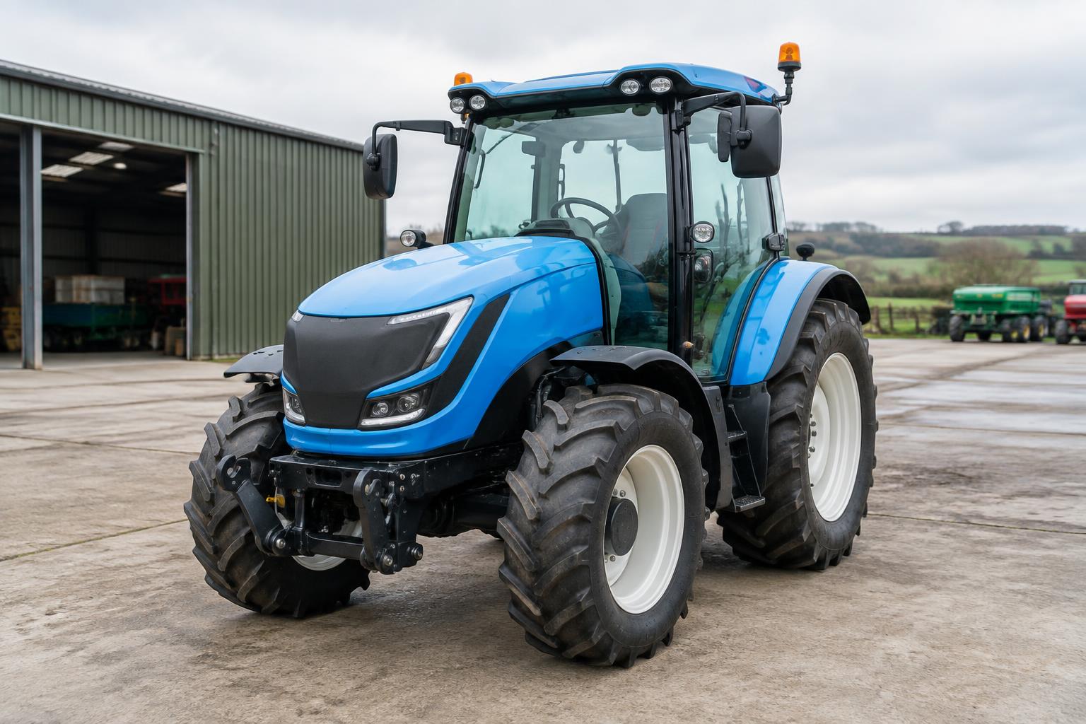 Blue battery-electric tractor parked outside a British farm machinery shed