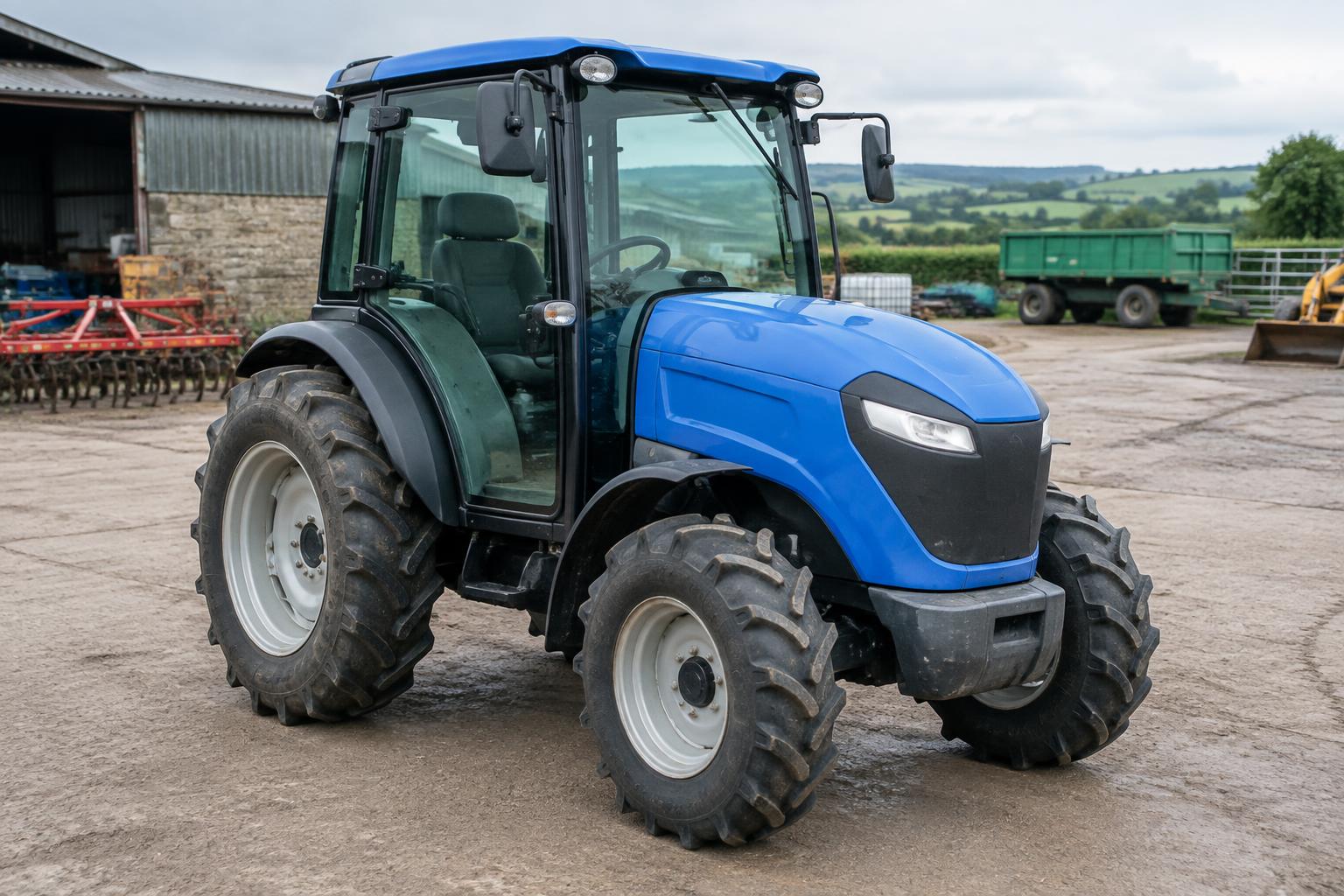 Used blue battery-electric tractor parked at a farm machinery yard